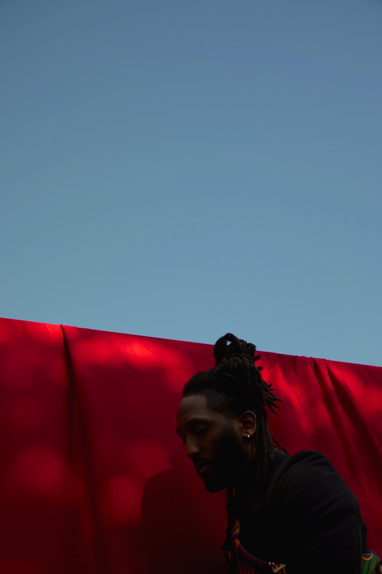 Shrodrick Spikes in front of a red backdrop under open sky