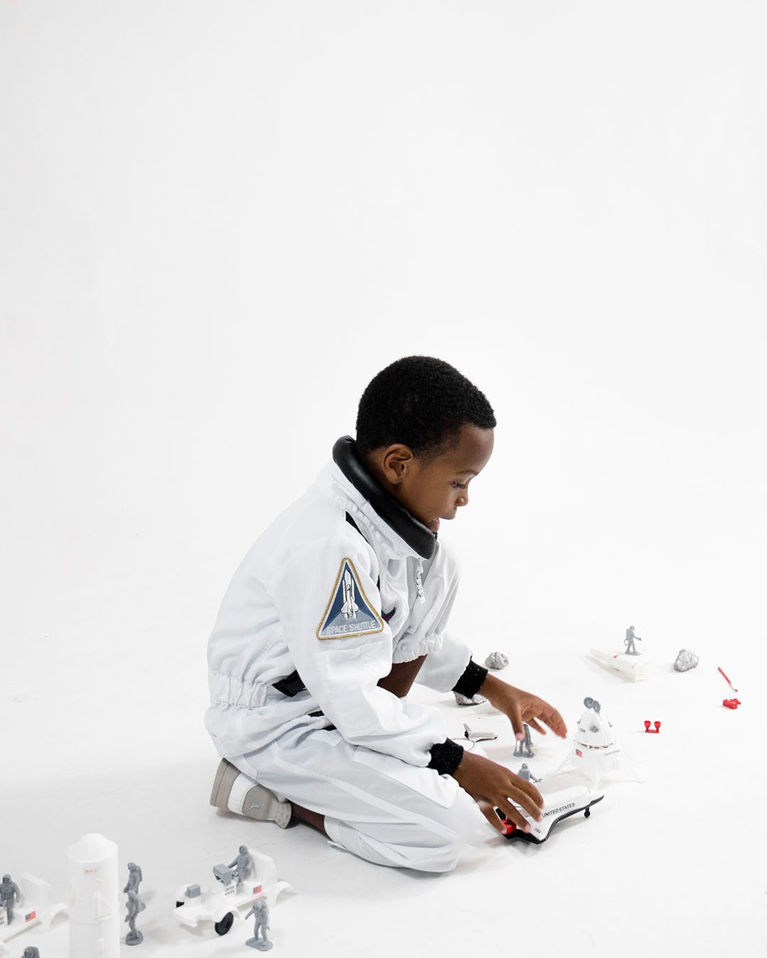 Child in a white suit arranging small figures